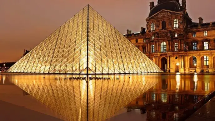 Stunning nighttime view of the illuminated Louvre Pyramid and reflection in Paris, France.